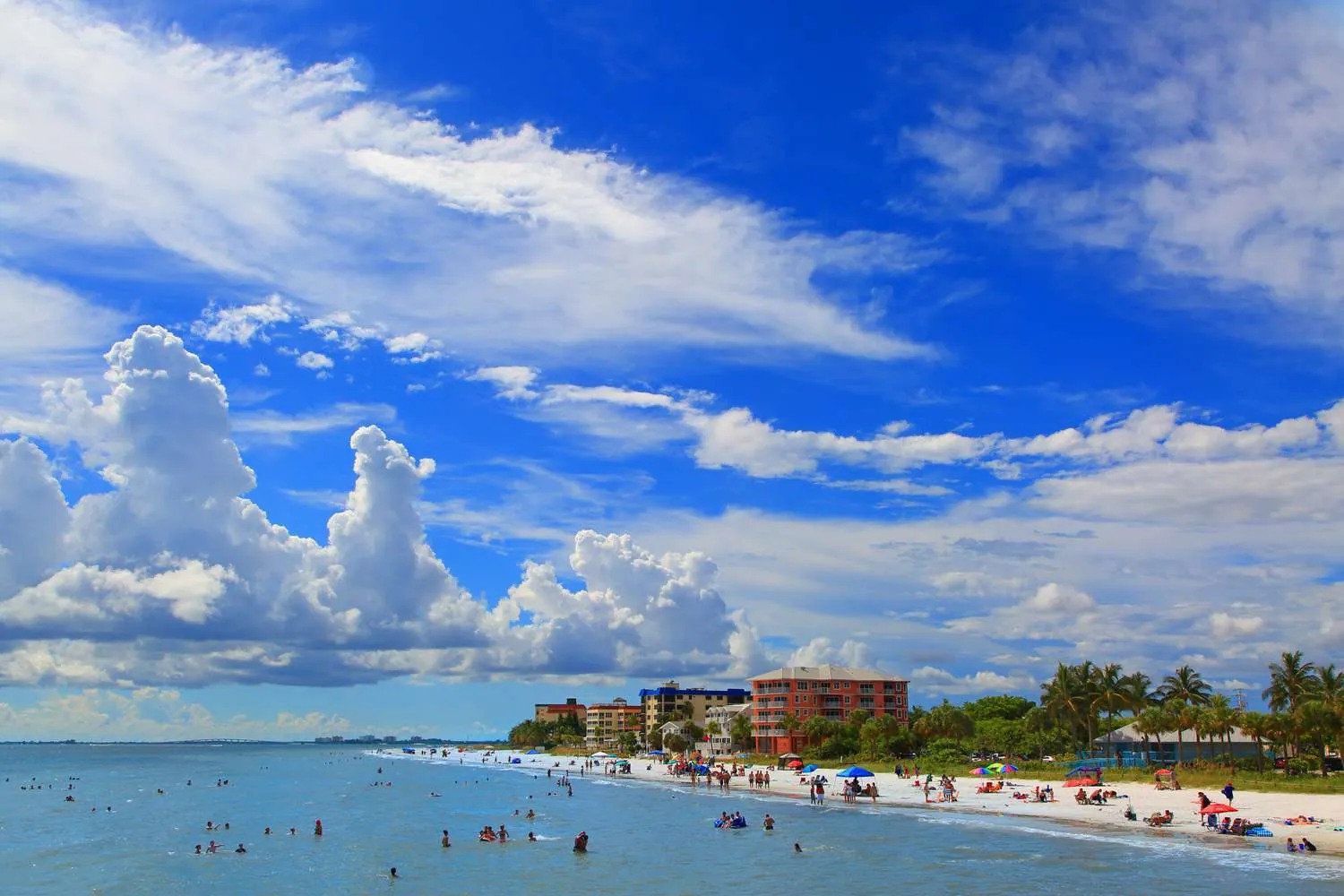 Fort Myers Beach shoreline with cumulus clouds and beachgoers in Southwest Florida